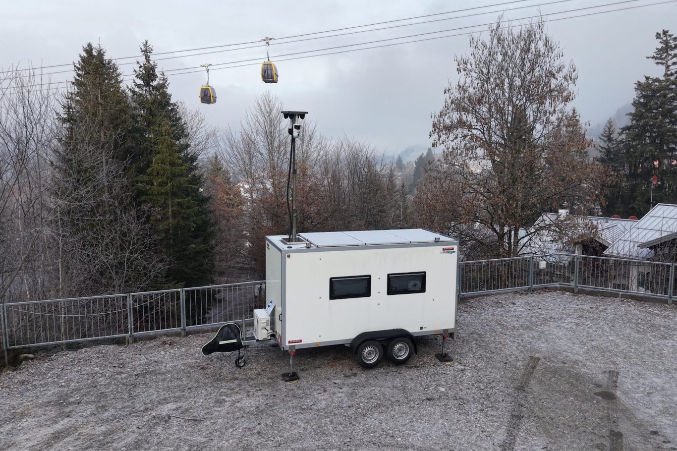 Mobile Sicherheitslösungen Weiße Container vor einem modernen Gebäude mit großen Glasfenstern.